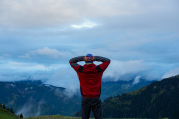 Happy traveler admires the huge clouds over the mountain valley