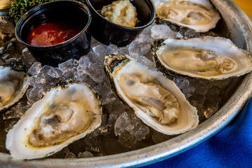 Detail of raw oyster served on iced platter with sauces in the background seafood appetizer or dinner