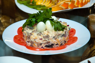 Salad with meat, quail eggs, tomato, cheese and greens. A background of a plate with oranges.