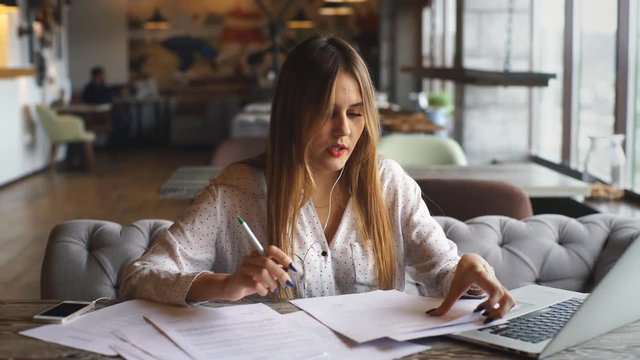 beautiful business woman signs the documents and listening to music on headphones