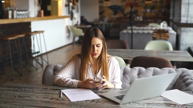 beautiful business woman signs the documents and listening to music on headphones