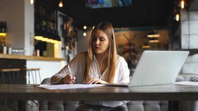 beautiful business woman signs the documents and listening to music on headphones