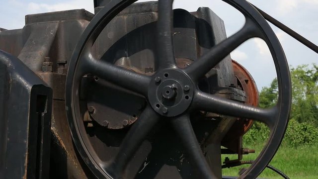 Big dynamo motor machine set working with belt over green garden outdoor background part of crude oil lifting pump - moving mechanical part of machine industrial concept