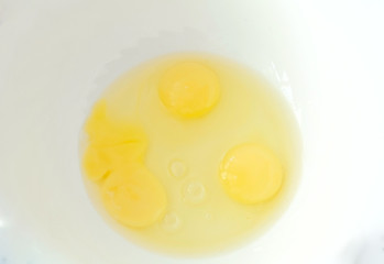 Closeup three fresh eggs in white bowl.