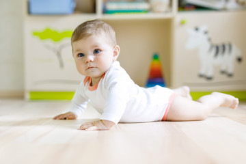 Fototapeta premium Cute baby girl learning crawling and sitting in children room