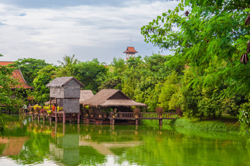 Obraz premium A traditional wooden Khmer house on stilts reflected by the water of the beautiful lake it stands on. Taken in the Cambodian Cultural Village in Siem Reap, Cambodia.