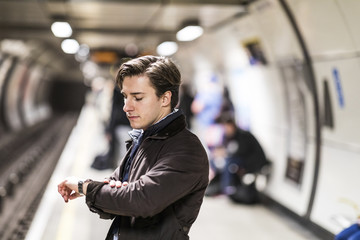 UK, London, businessman waiting at underground station checking the time