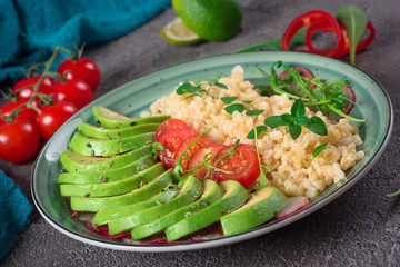 Porridge bulgur with salad avocado, tomatoes and arugula. Rustic concrete background. Top view