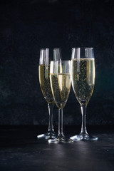Elegant glasses of yellow champagne with bubbles on black background with reflection
