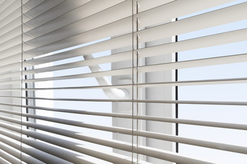 White plastic window with blinds close-up against a blue sky.