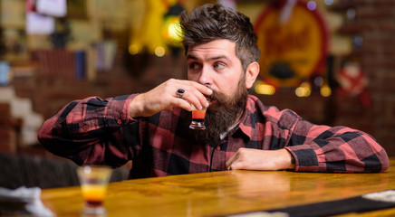 Hipster on thoughtful face drinks shot cocktail.