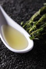 Plant oil  with thyme branches on a background of black sesame.