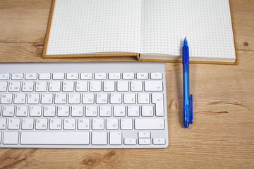 Computer keyboard and notebook are on the table