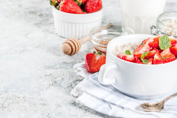 Healthy summer breakfast, overnight oatmeal with fresh strawberry and milk, grey stone background