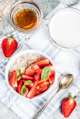 Healthy summer breakfast, overnight oatmeal with fresh strawberry and milk, grey stone background