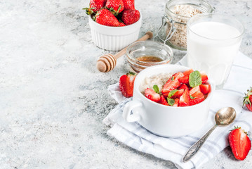 Healthy summer breakfast, overnight oatmeal with fresh strawberry and milk, grey stone background