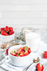 Healthy summer breakfast, overnight oatmeal with fresh strawberry and milk, grey stone background