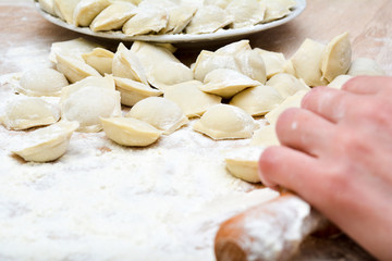 Fototapeta na wymiar Preparation of dumplings - table, flour, rolling pin, women's hands.