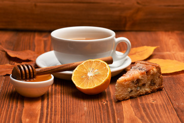 Tea cup with honey, wooden spoon and cake, autumn composition