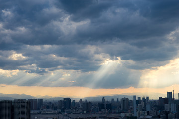 Fototapeta premium Top view of modern city with lights of sunset through clouds