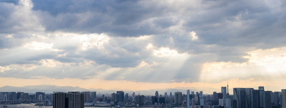 Top view of modern city with lights of sunset through clouds