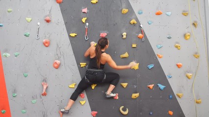 Girl climbing indoors, view from the back.
