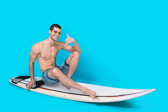 Cheerful surfer showing call me sign