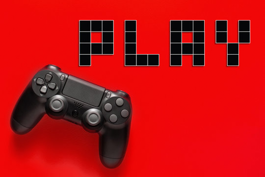 Black modern gamepad and word play on a colored background . Gaming concept