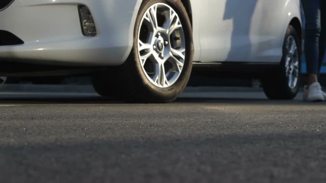 Close-up of woman's legs near her car. Lady coming out white auto, closing door.