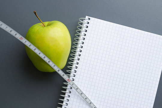 blank notebook with apple and measuring tape