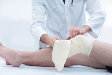 Fototapeta premium doctor bandaging patient knee