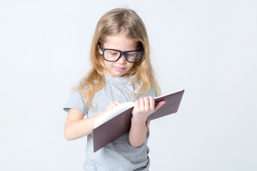 Little girl in glasses with a book in her hands.