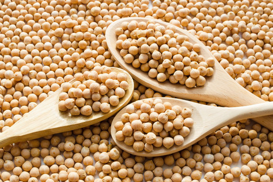 dry raw chickpeas in wooden spoons
