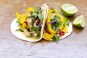 Corn tortillas with fresh vegetables, grilled chicken fillet, lime on rustic wooden background. Side view, closeup.