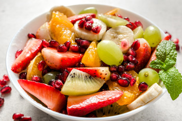 Mixed fruit salad, closeup on white wooden background, clean eating and healthy food concept