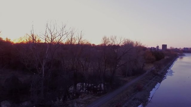 Backwards tracking shot of a forest near a river at sunset.