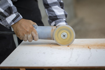 Image of worker using tool to cut white tile.