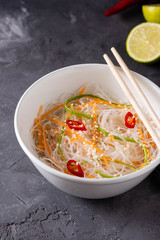 Bean thread noodles salad with cucumber and carrot on a plate close-up.