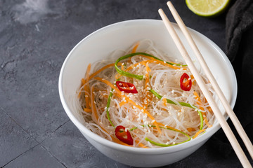 Bean thread noodles salad with cucumber and carrot on a plate close-up.