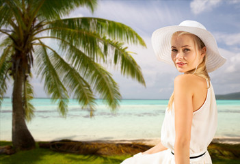 travel, tourism and summer vacation concept - beautiful woman in hat enjoying sun over tropical beach background in french polynesia