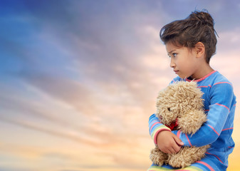 childhood, sadness, loneliness and people concept - sad little girl with teddy bear toy over...