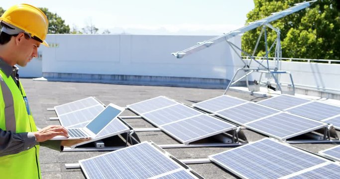 Male worker using laptop at solar station 