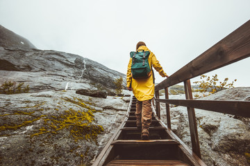Tourist woman with backpack climbing up stairs in rocky mountains Traveling alone adventure...