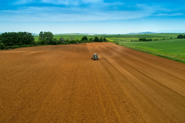 Aerial shot of  Farmer with a tractor on the agricultural field sowing.