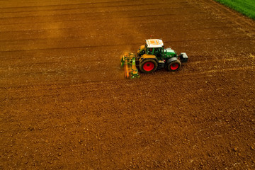 Obraz premium Aerial shot of Farmer with a tractor on the agricultural field sowing.