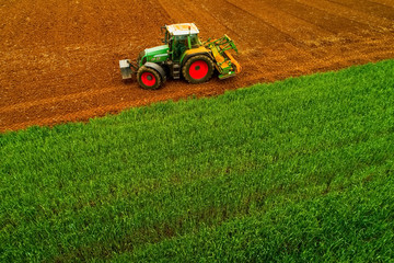 Obraz premium Aerial shot of Farmer with a tractor on the agricultural field sowing.