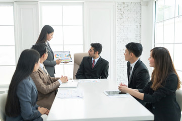 A confident business team of mixed ages and ethnicity are holding a meeting in a modern office. They are discussing ideas for their business development.