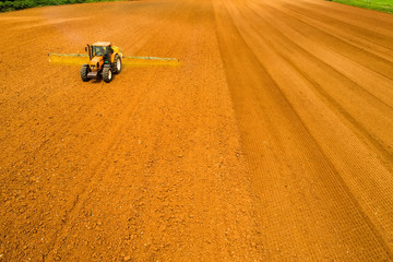 Aerial shot of  Farmer with a tractor on the agricultural field sowing.