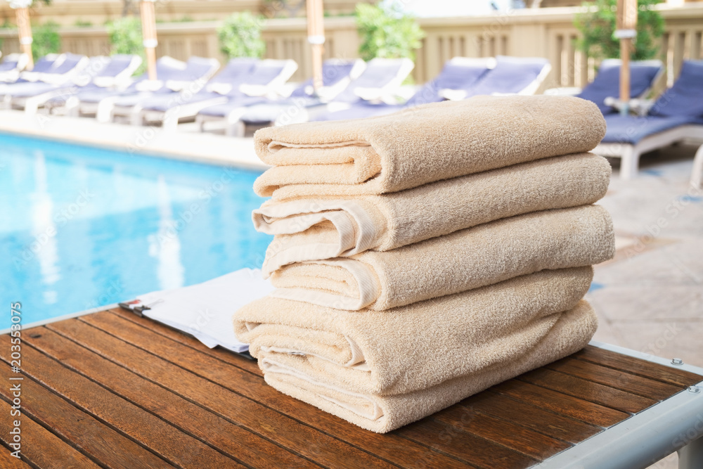 Aufkleber stack of clean towel on wooden table near pool for service customer