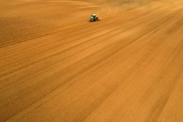 Aerial shot of  Farmer with a tractor on the agricultural field sowing.